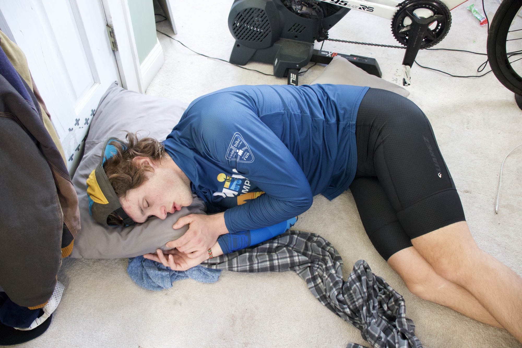 Pat asleep on the floor in full cycling kit, mid 24-hour ride