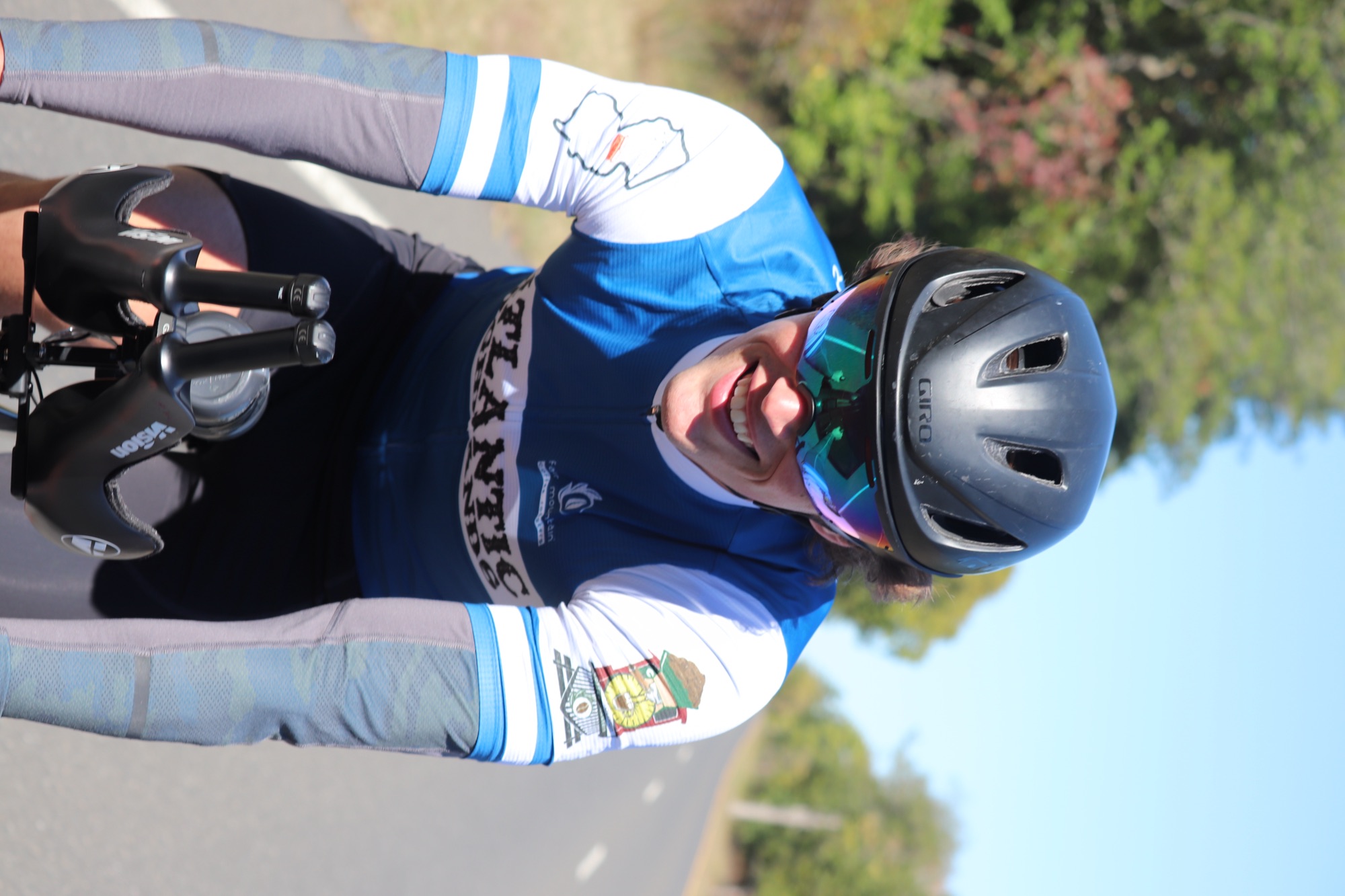 Patrick grinning mid-ride on a sunlit road